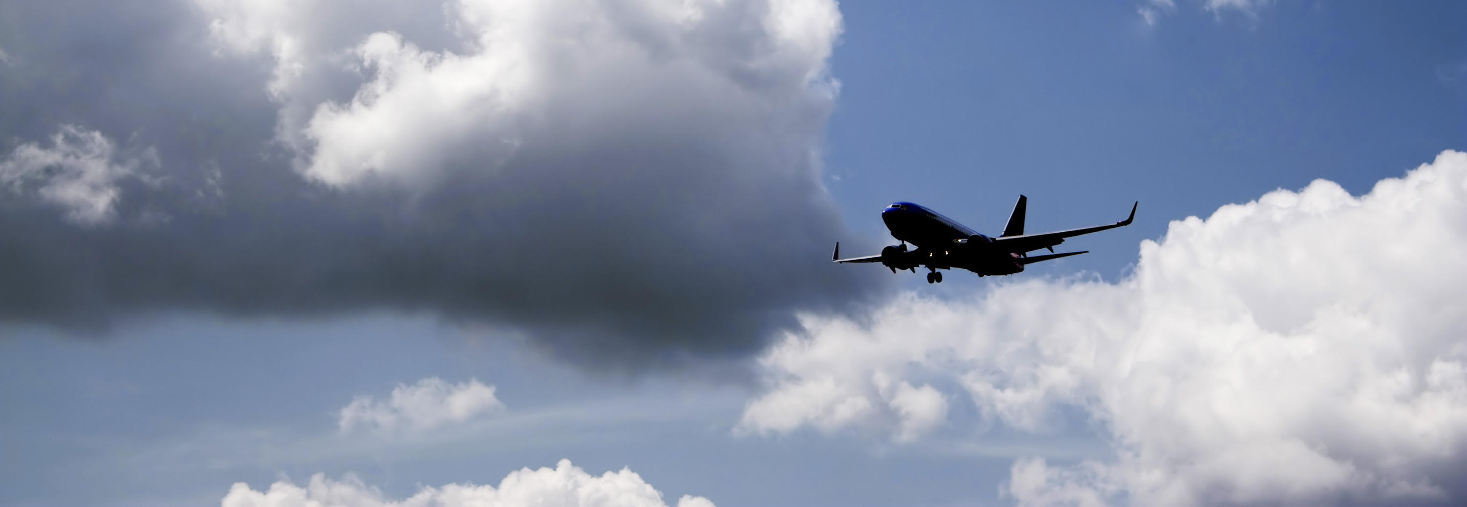 Commerical passenger airplane in blue sky with white puffy clouds flying in to land Plane in blue sky